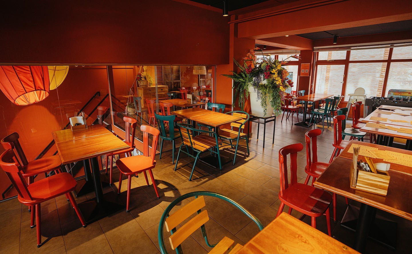 The interior of halal restaurant MeMe in Rotterdam, Netherlands, showing colorful chairs and wooden tables in a warm, inviting atmosphere.