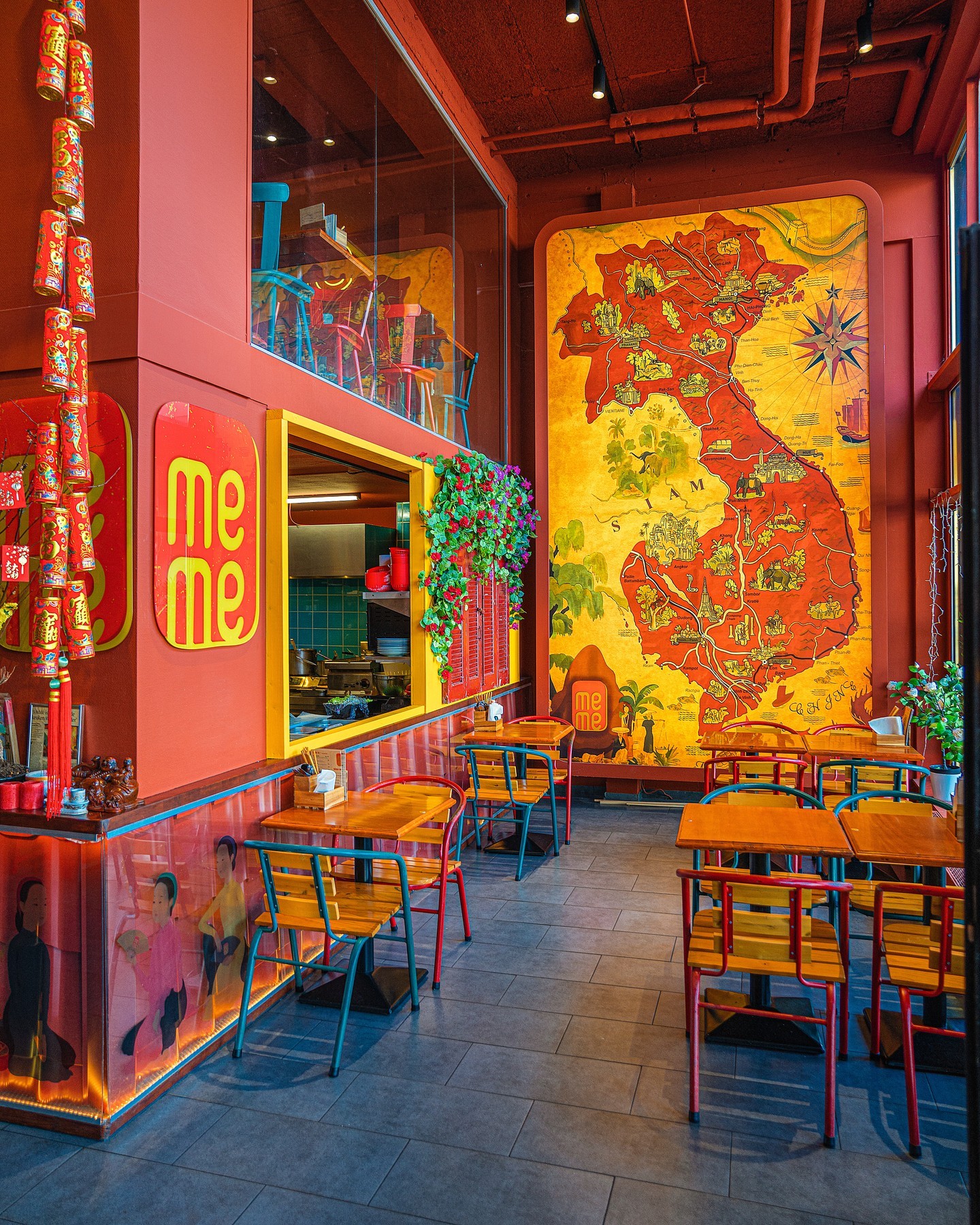 The interior of halal restaurant MeMe in Rotterdam, Netherlands, showing colorful chairs, a large mural of Vietnam, and decorative elements like hanging lanterns and plants.