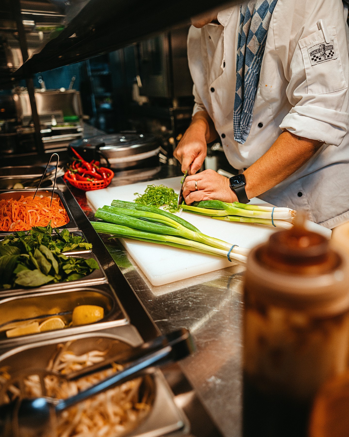 The interior of halal restaurant MeMe in Rotterdam, Netherlands, showing a chef preparing vegetables on a cutting board with various ingredients in the background.