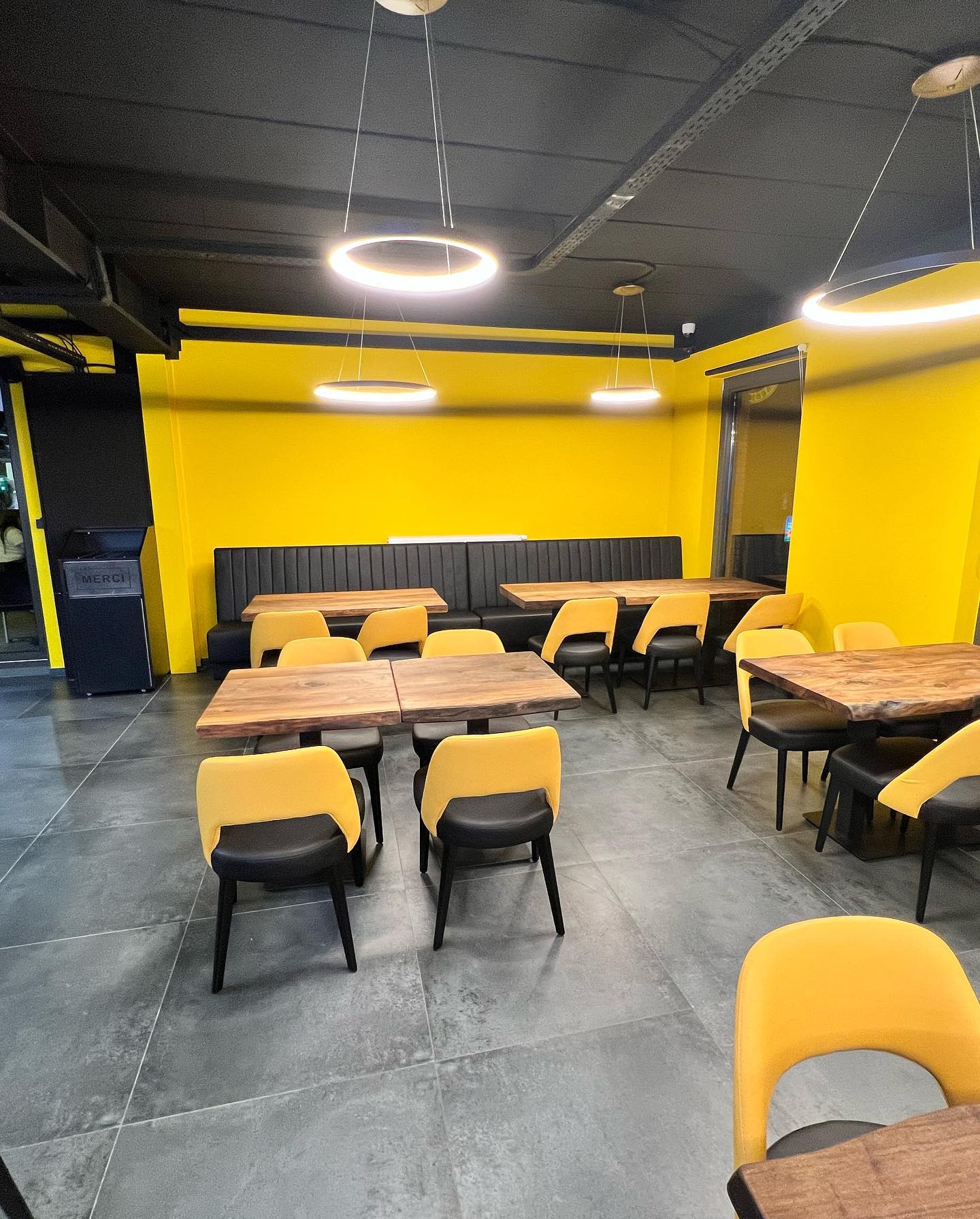 The interior of halal restaurant City Food Lounge in Genk, Belgium, showing yellow walls, black seating, and wooden tables.