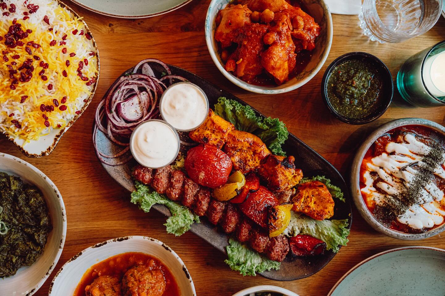 A platter of grilled meats, including kebabs and chicken, served with rice, sauces, and vegetables at Kite, a halal restaurant in Rotterdam, Netherlands.