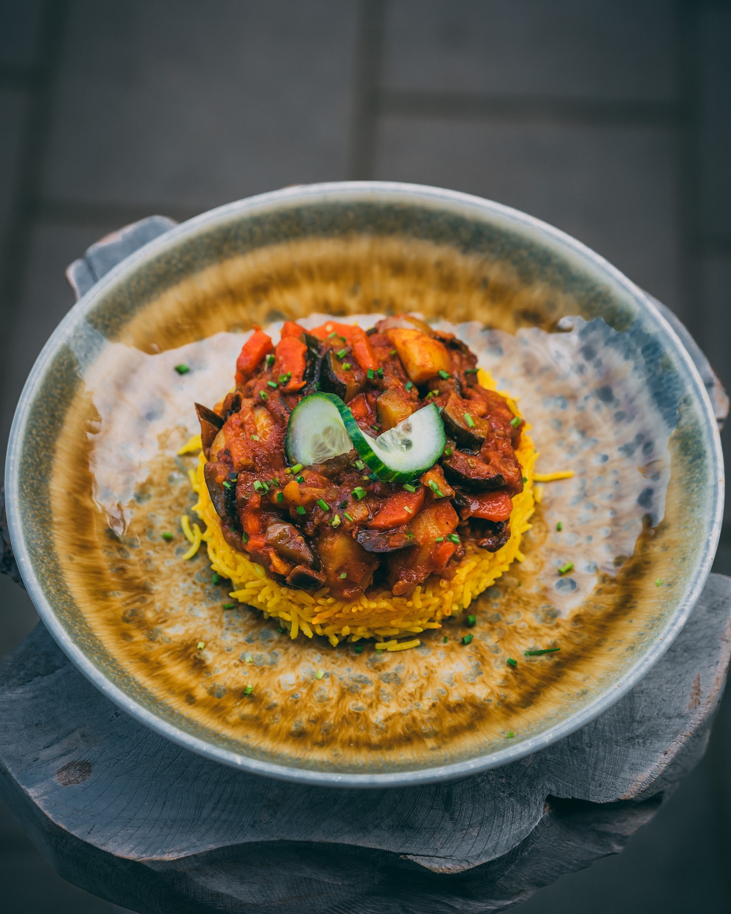 A plate of yellow rice topped with a spicy vegetable stew, garnished with cucumber slices, at Malva, a halal restaurant in Amsterdam, Netherlands.
