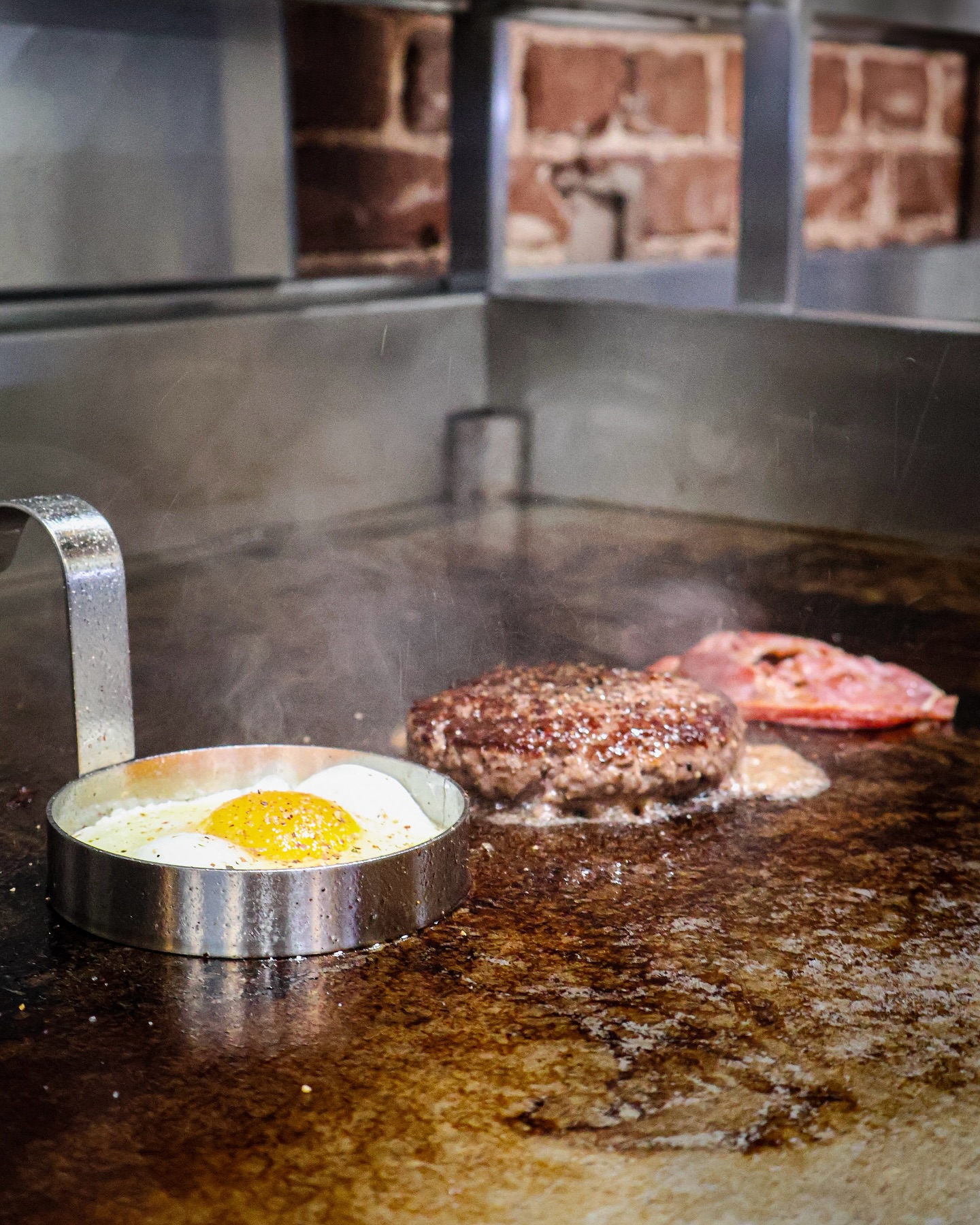 A burger with a fried egg and bacon on a grill at Just Burgers, a halal restaurant in Gorinchem, Netherlands.