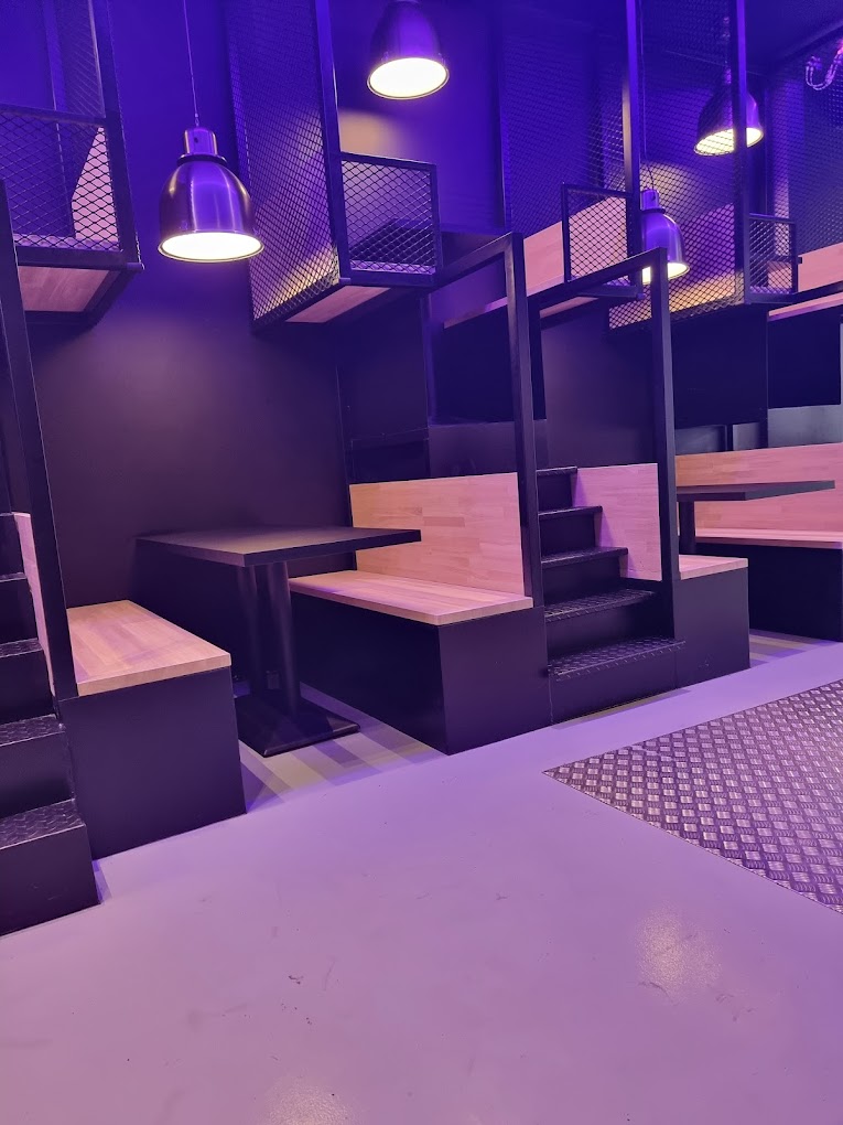 The interior of halal restaurant Nub Smashburger in Antwerpen, Belgium, showing modern seating arrangements with wooden tables and purple lighting.