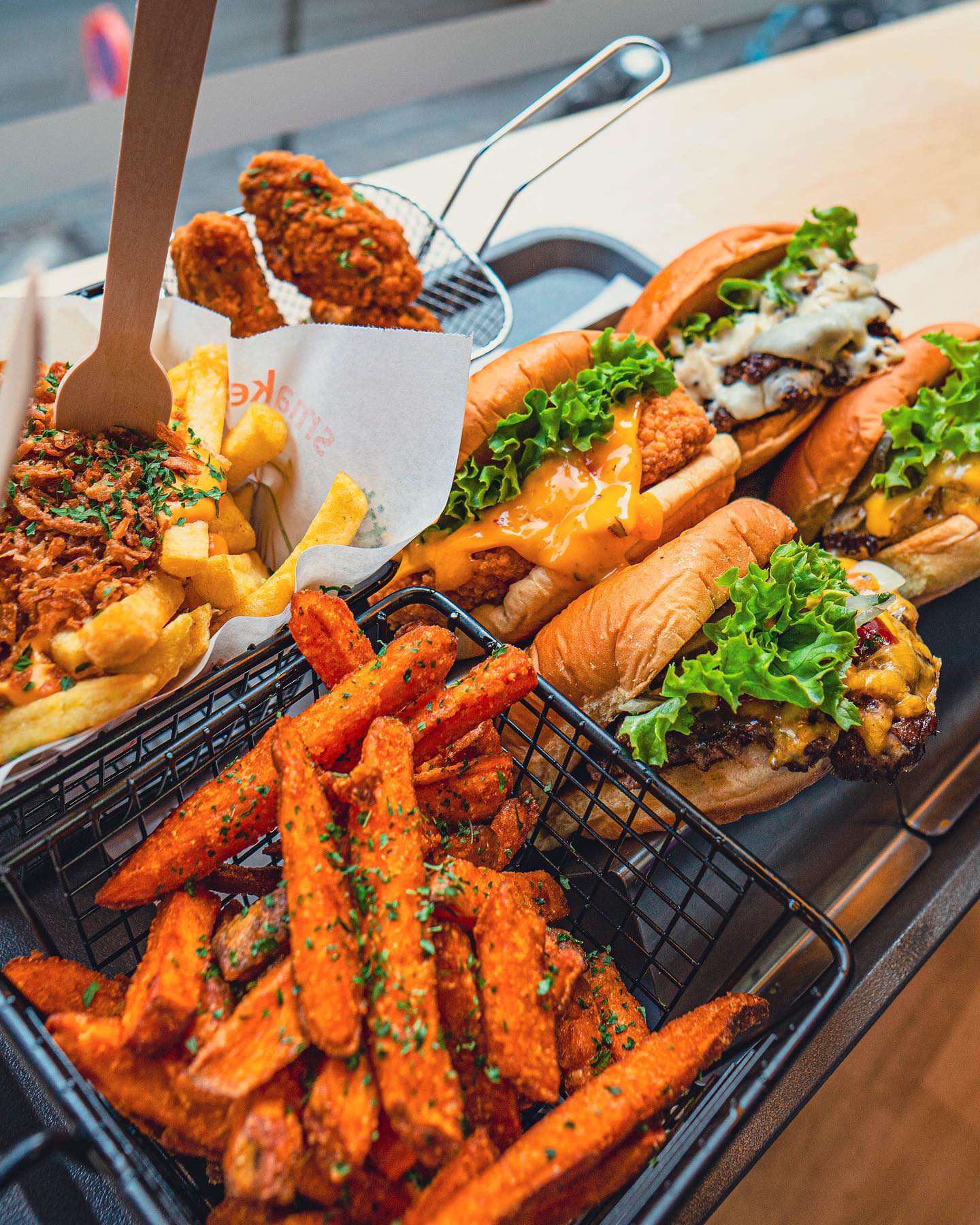 A platter of burgers, sweet potato fries, and fried chicken at Nub Smashburger, a halal restaurant in Antwerpen, Belgium.