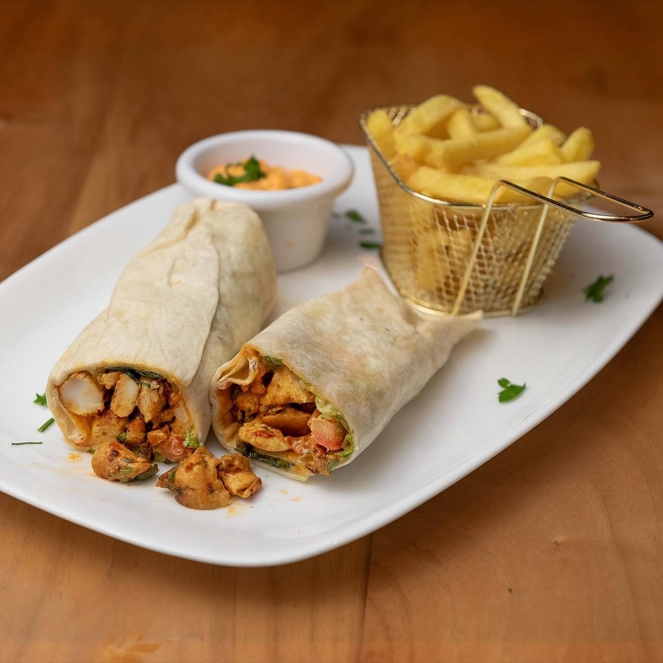 A plate of two chicken wraps with vegetables and sauce at Paparazzi Bistro, a halal restaurant in Antwerpen, Belgium.