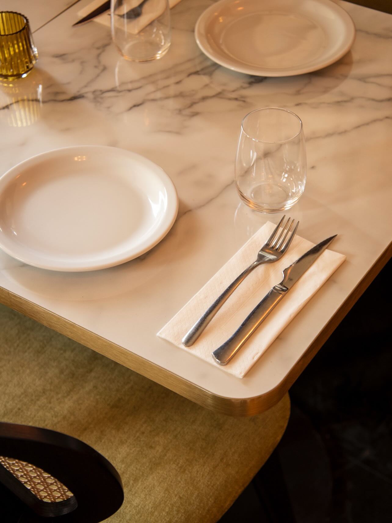 The interior of halal restaurant Le Petit La Ruche in Antwerpen, Belgium, showing a marble table with white plates, cutlery, and glassware.