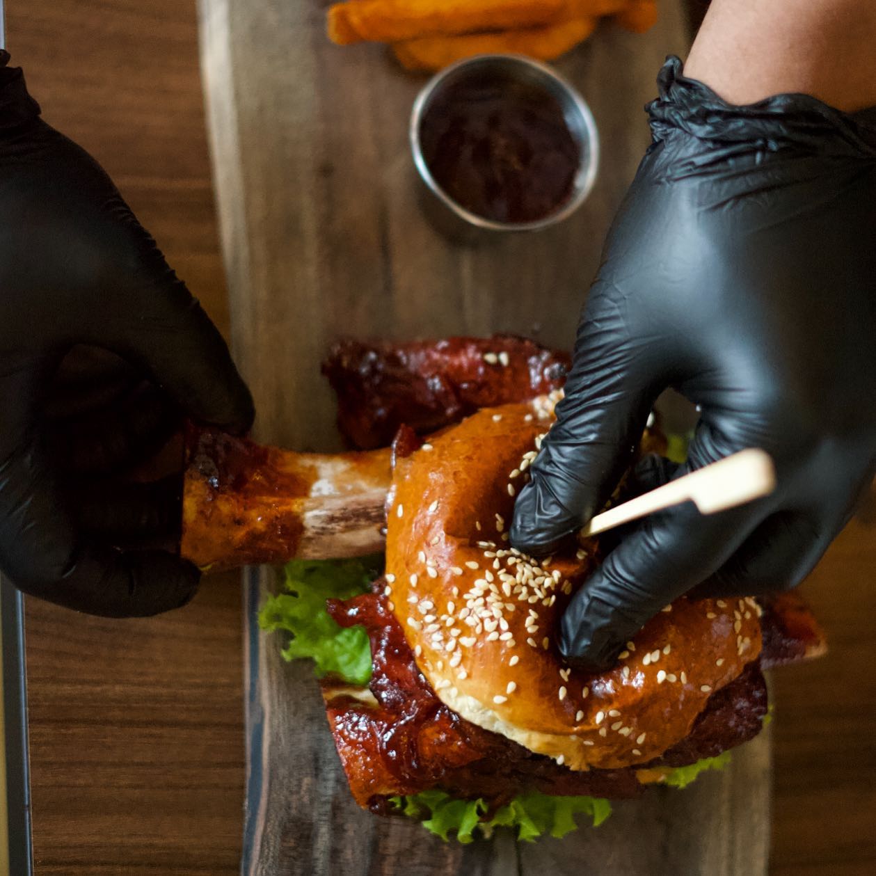 A close-up of a burger with a large piece of meat on a wooden board at Le Petit La Ruche, a halal restaurant in Antwerpen, Belgium.