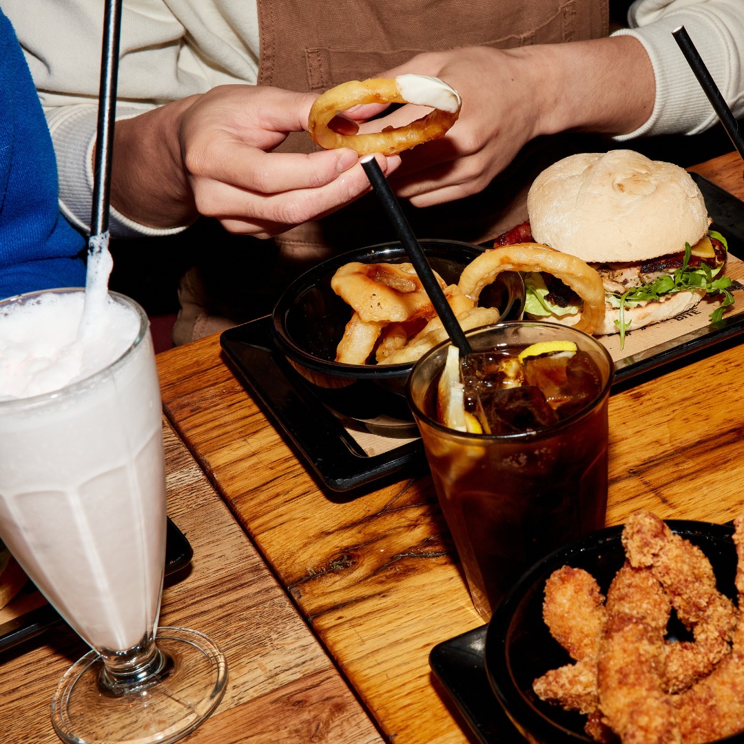 A plate of onion rings, a burger with lettuce, and two drinks at Burger Bar, a halal restaurant in Amsterdam, Netherlands.