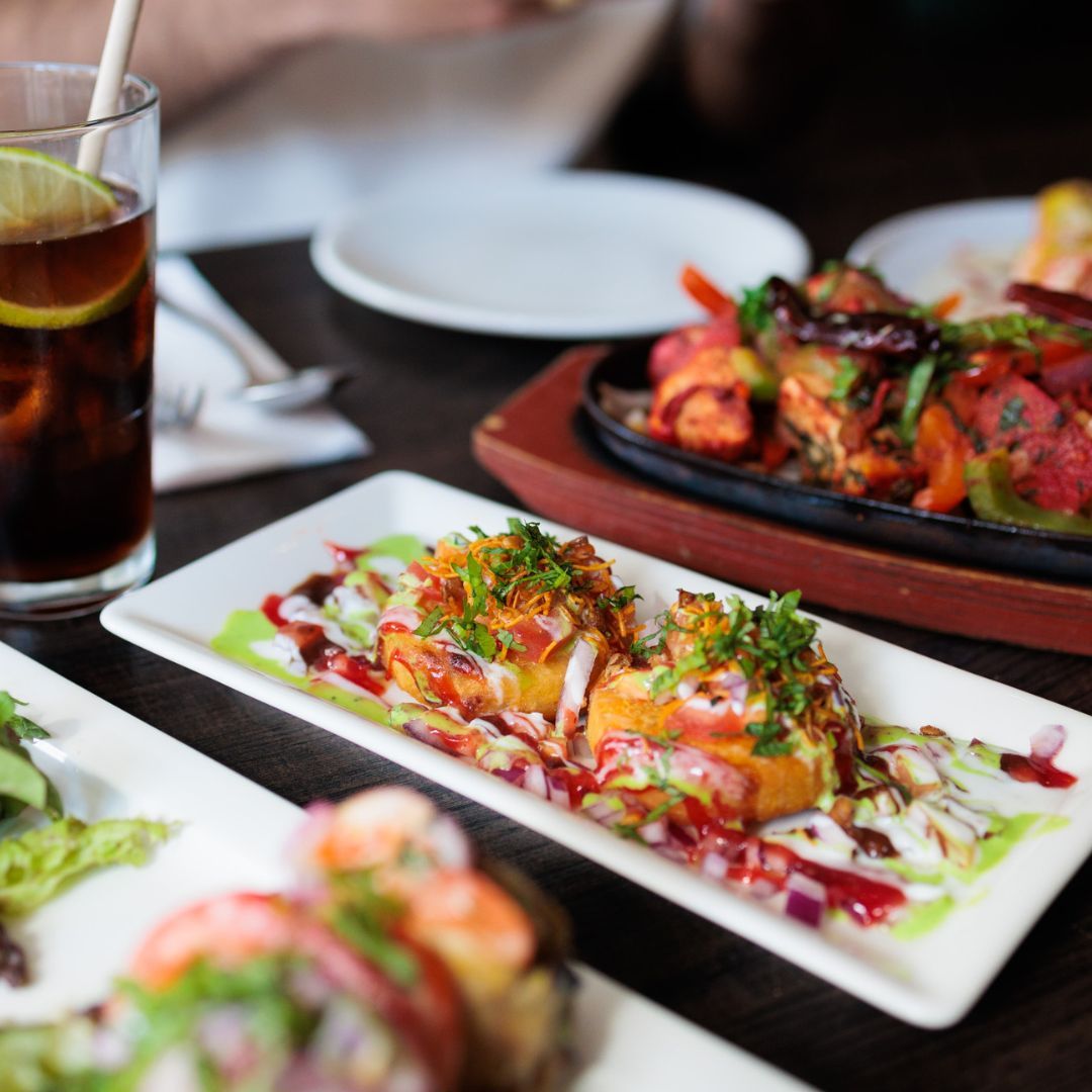 A plate of colorful Indian snacks topped with herbs and sauces at Guru, a halal restaurant in Amsterdam, Netherlands.