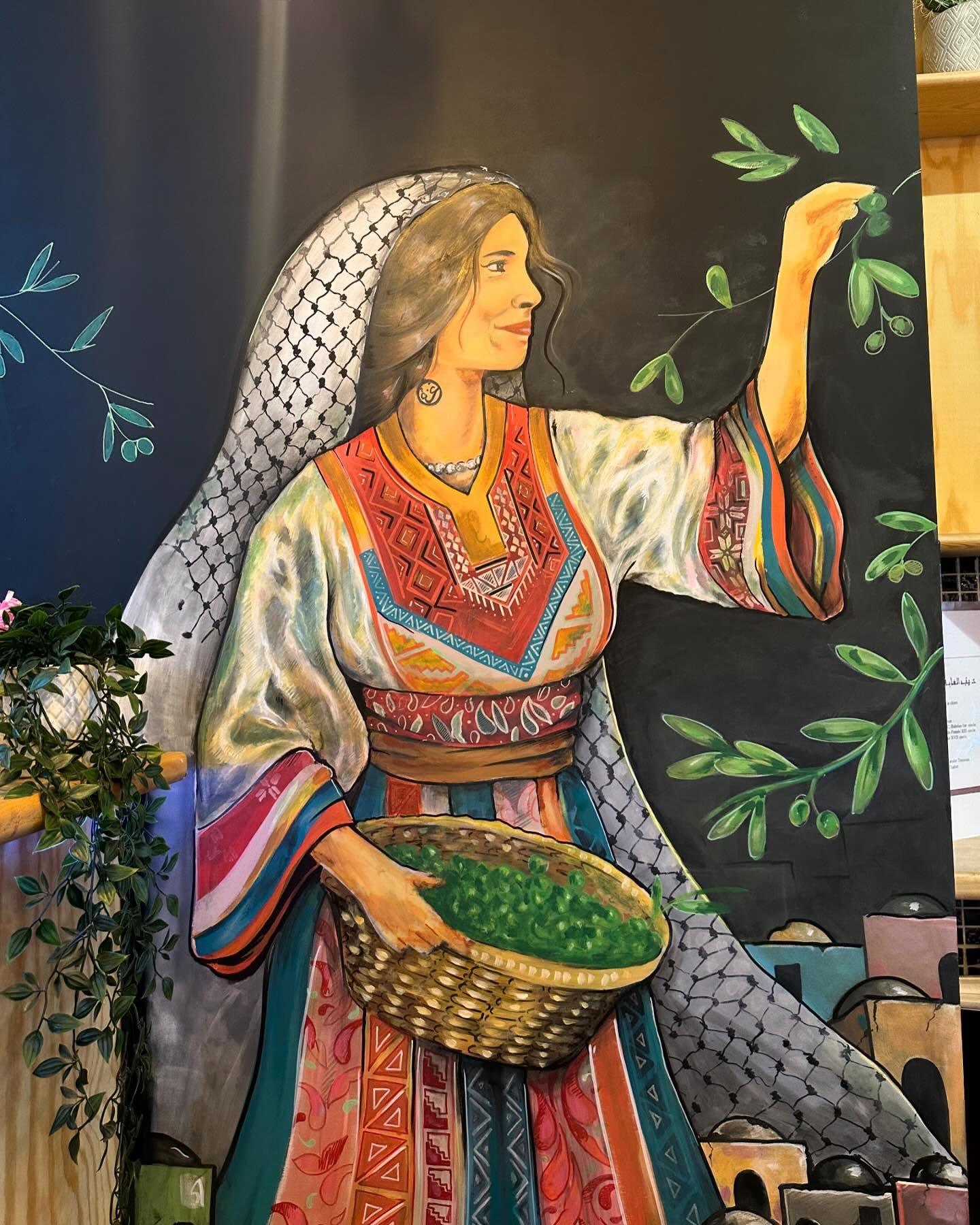 A mural of a woman in traditional attire holding a basket of greens and reaching for olive branches at Olive, a halal restaurant in Saint-Gilles, Belgium.