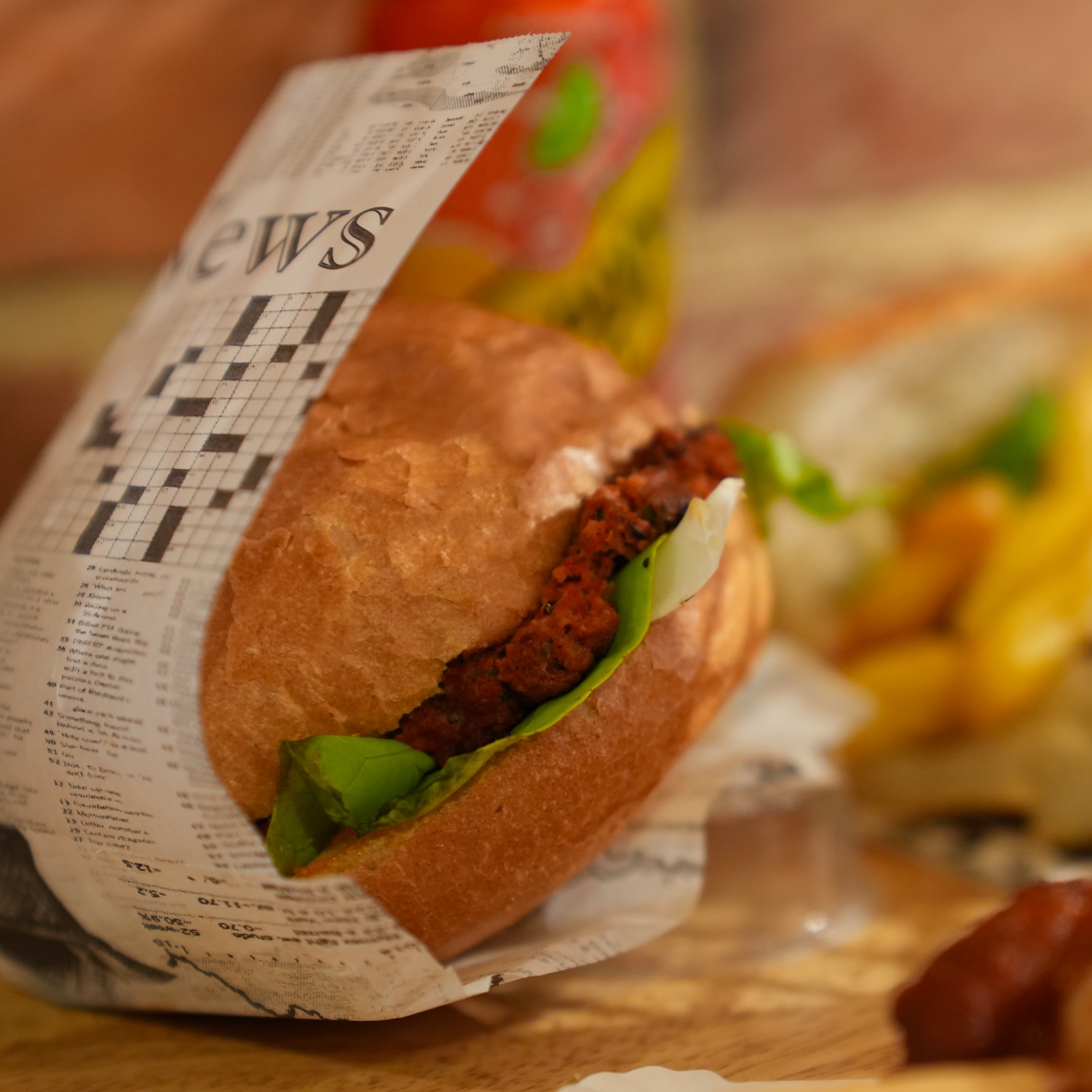 A burger wrapped in newspaper with a patty, lettuce, and sauce at Joe La Frite, a halal restaurant in Bruxelles, Belgium.