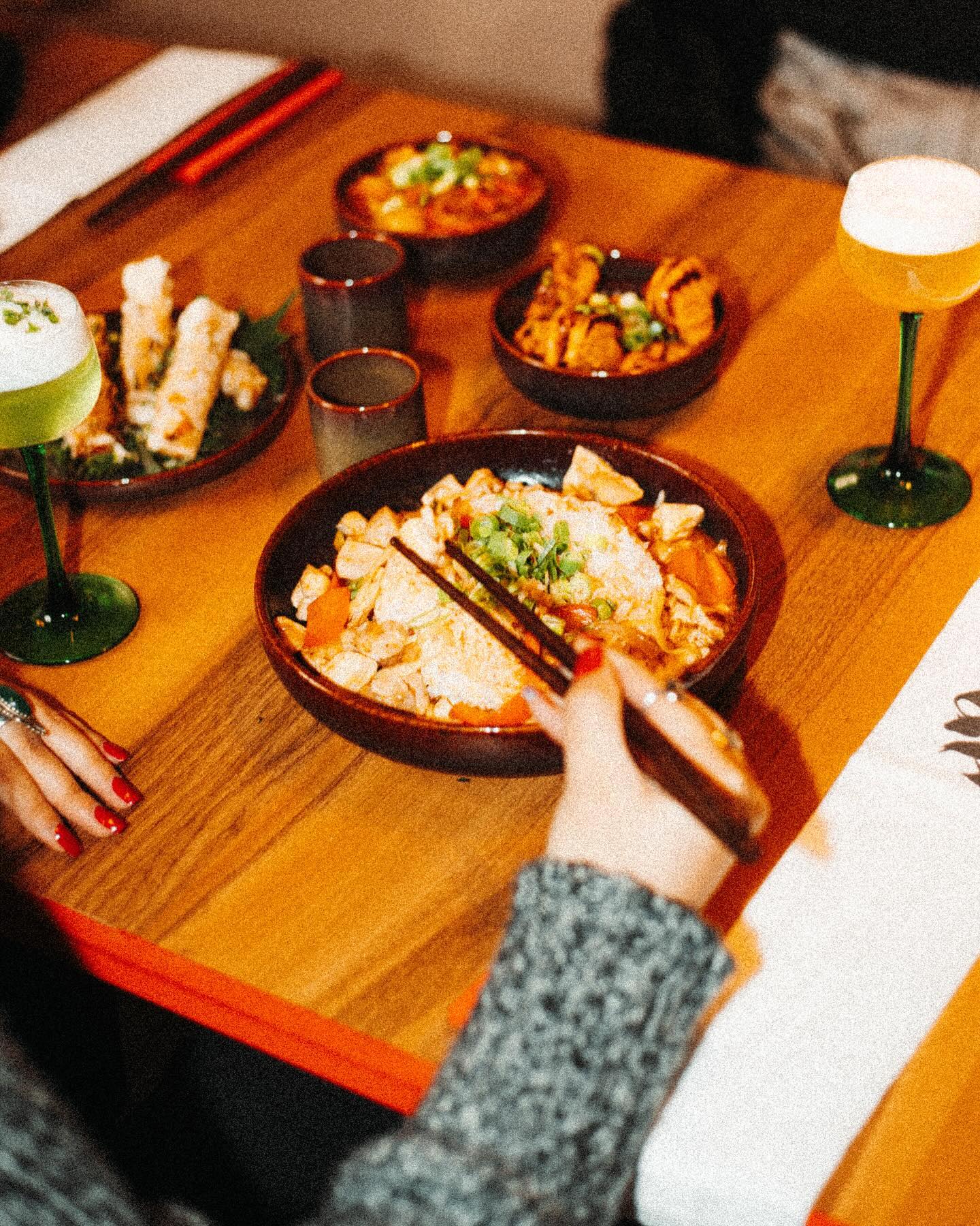 Een kom met kip en groenten roerbak met eetstokjes bij NOYA, een halal restaurant in Schaerbeek, België.