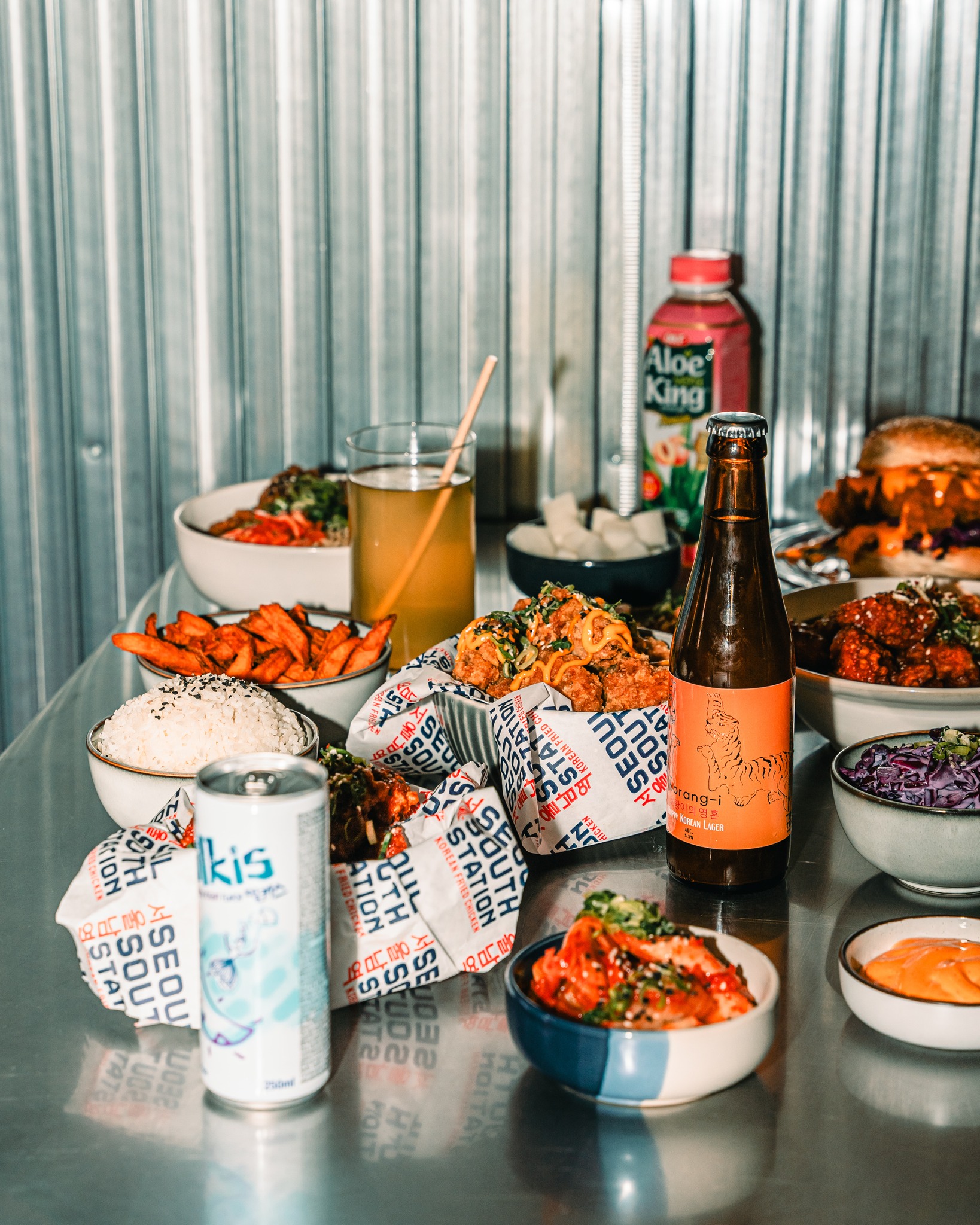 Een verscheidenheid aan halal gerechten, waaronder gefrituurde kip, rijst, zoete aardappelfrites en drankjes bij halal restaurant Seoul South Station in Brussel, België.