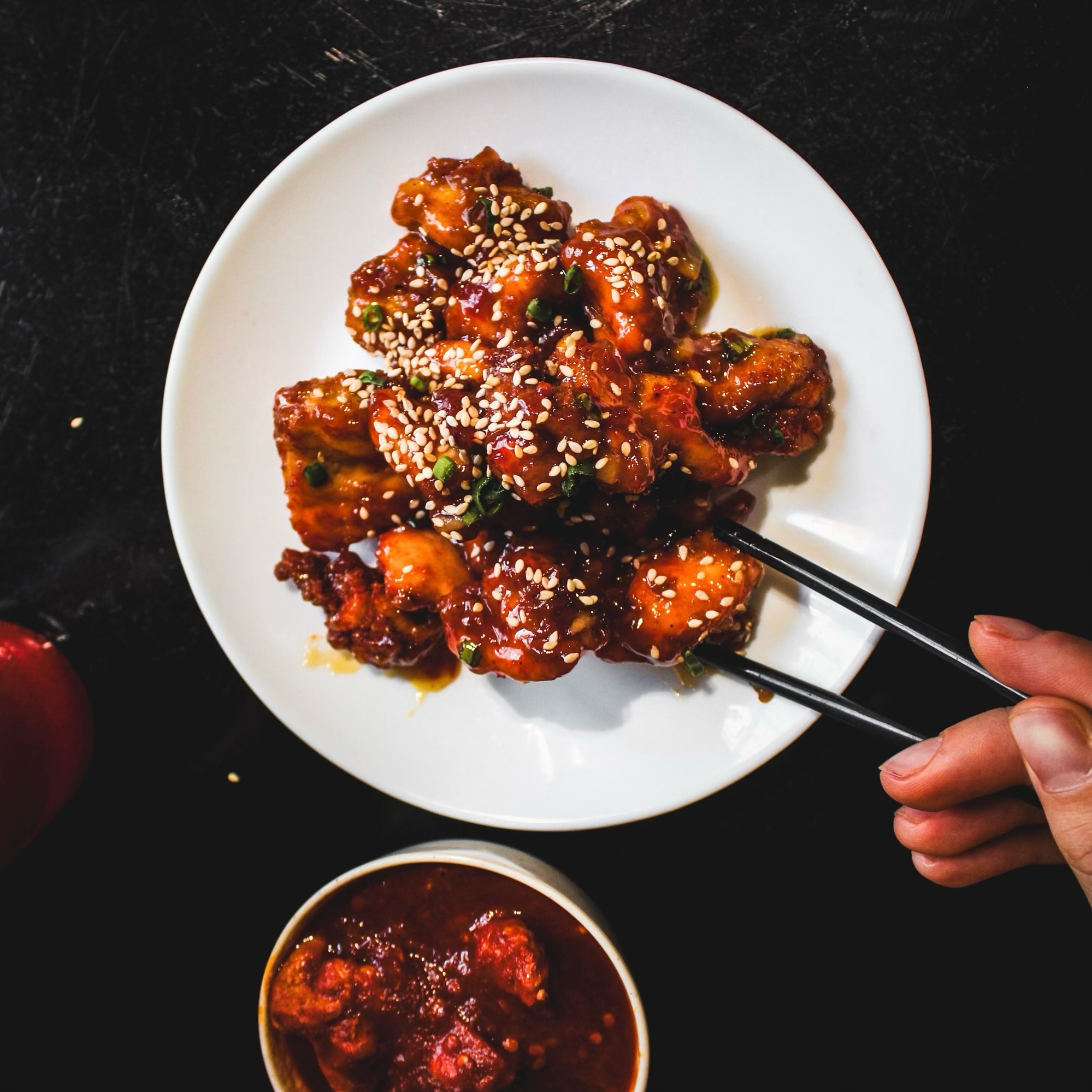 A plate of sesame chicken with sauce at Leuven Chicken and Rice, a halal restaurant in Leuven, Belgium.