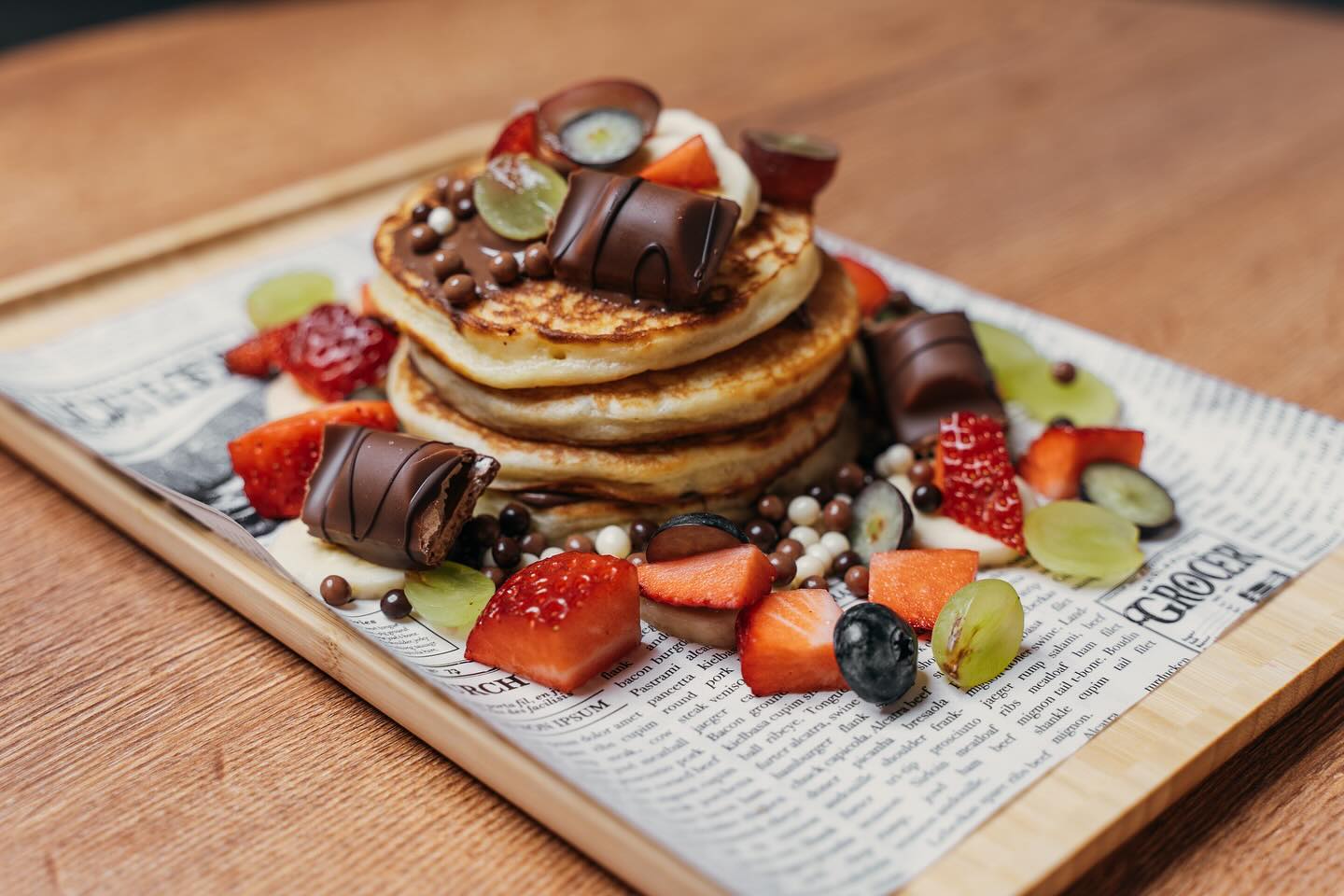 A stack of pancakes topped with chocolate, strawberries, grapes, and colorful candy at Freshmade, a halal restaurant in Wijnegem, Belgium.
