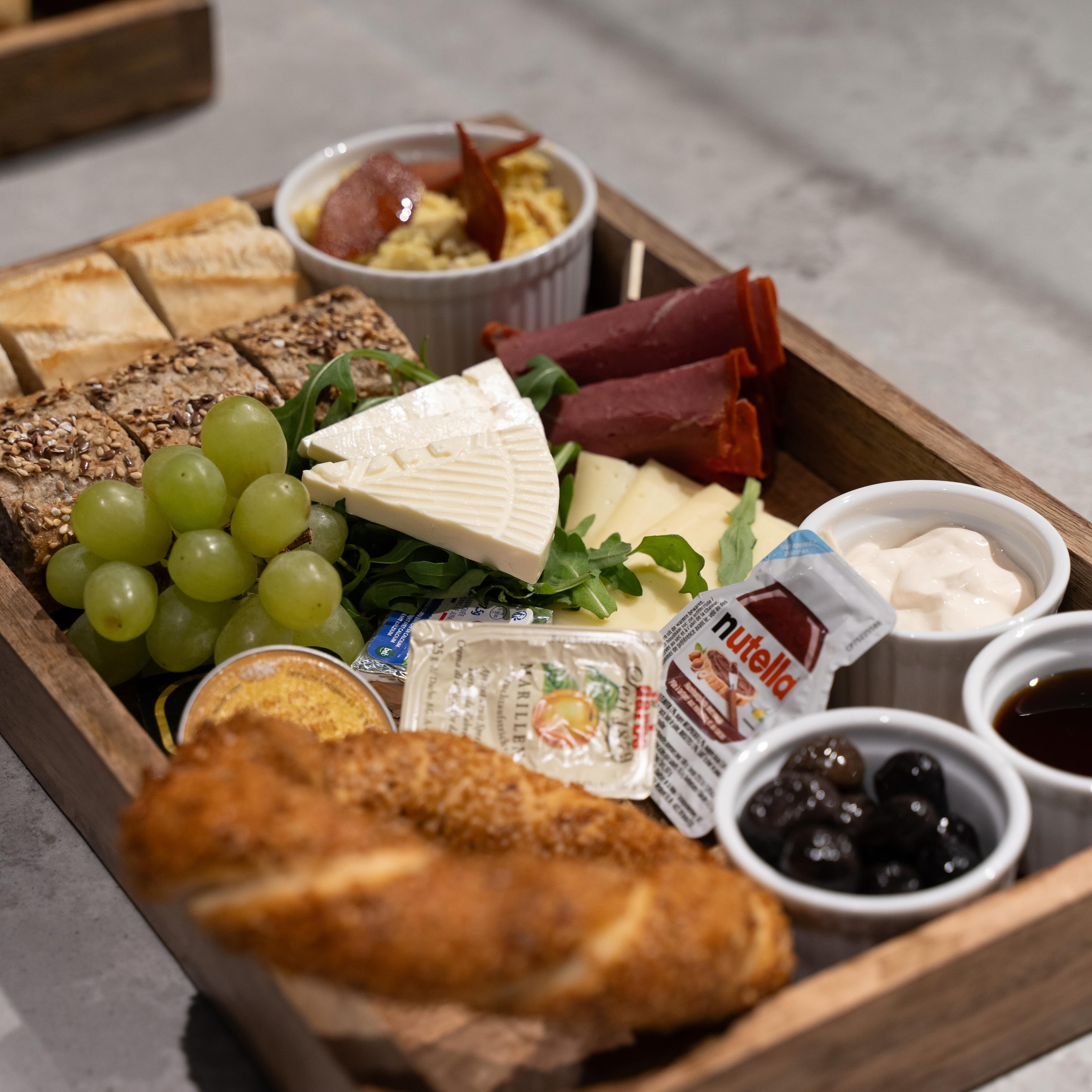 A wooden platter with assorted cheeses, meats, grapes, bread, and condiments at Freshmade, a halal restaurant in Wijnegem, Belgium.