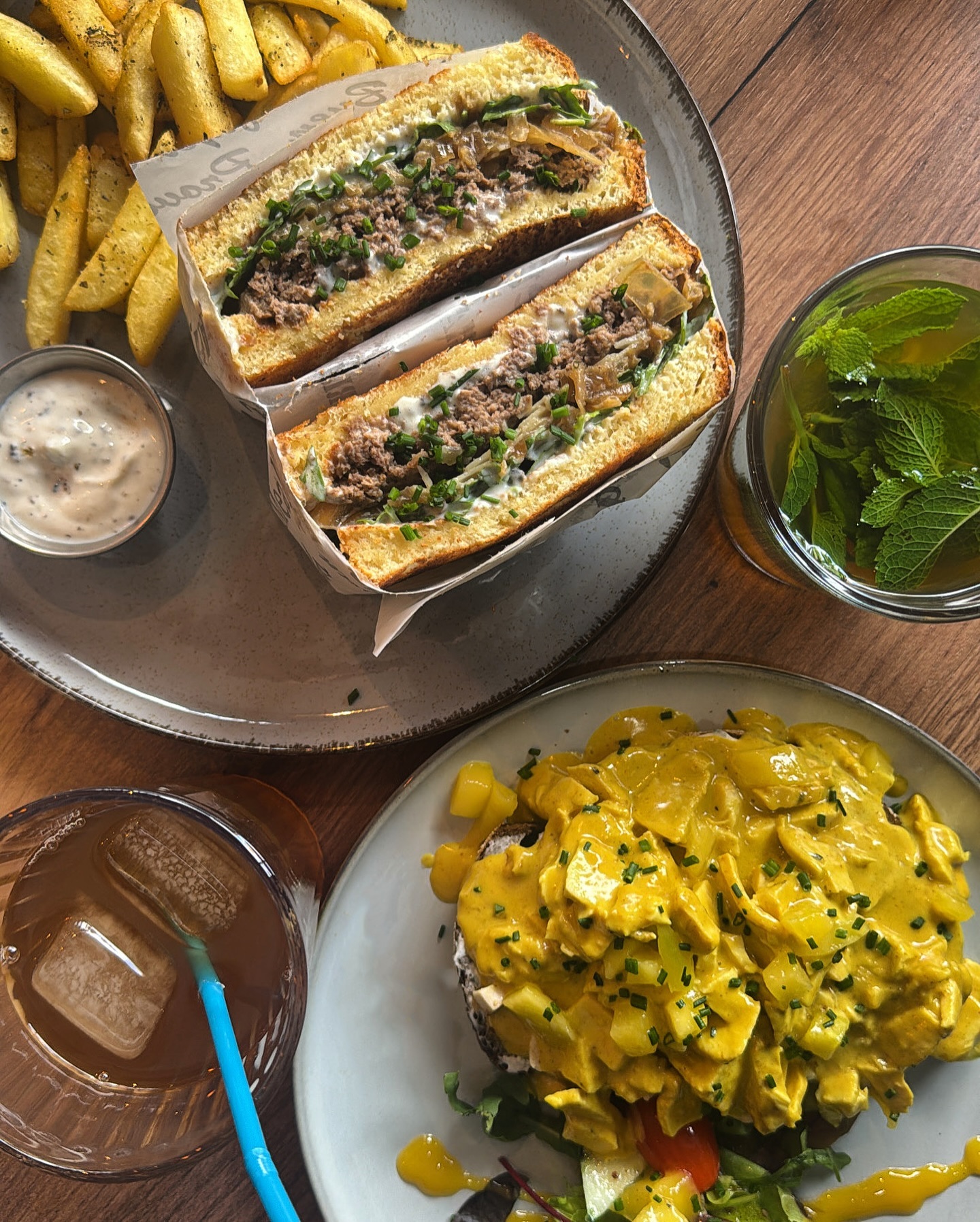A plate of beef sandwich with green onions and sauce, served with fries and a salad, at Baba Brunch, a halal restaurant in Koekelberg, Belgium.