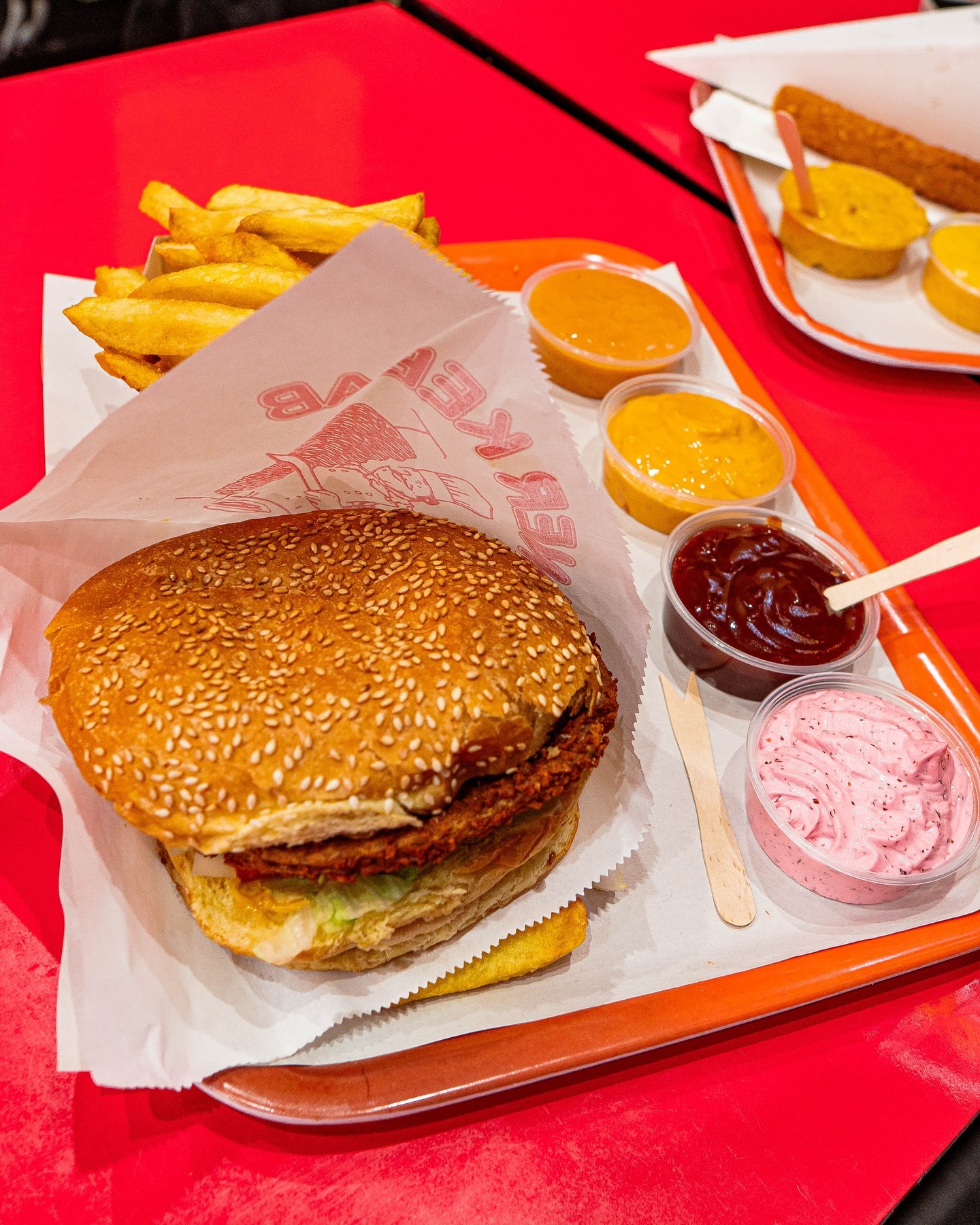 Een sesamburger met frietjes en verschillende sauzen bij Batata, een halal restaurant in Anderlecht, België.