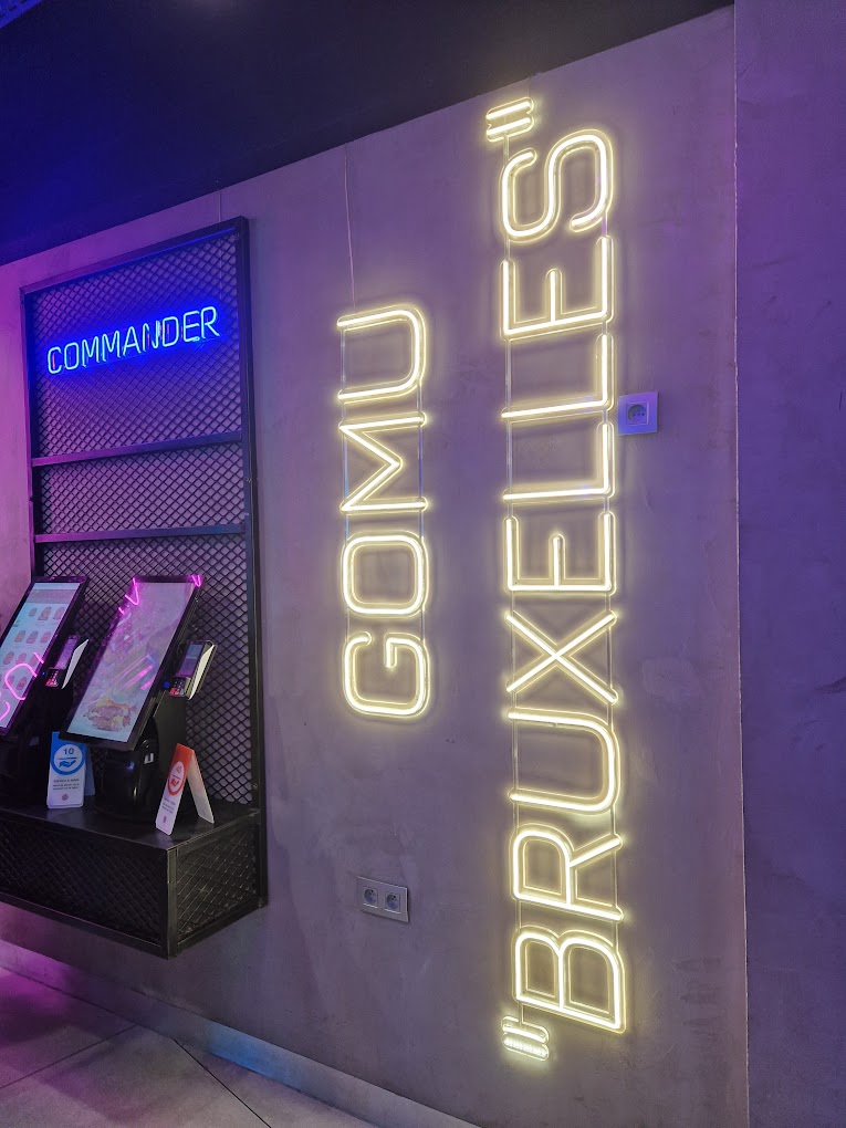 Het interieur van halal restaurant GOMU in Brussel, België, met neonverlichting en digitale bestelzuilen.