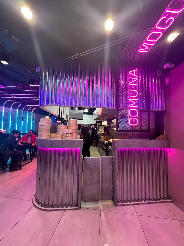 Het interieur van halal restaurant GOMU in Brussel, België, met een modern ontwerp met neonverlichting, metalen accenten en een zichtbare keuken.