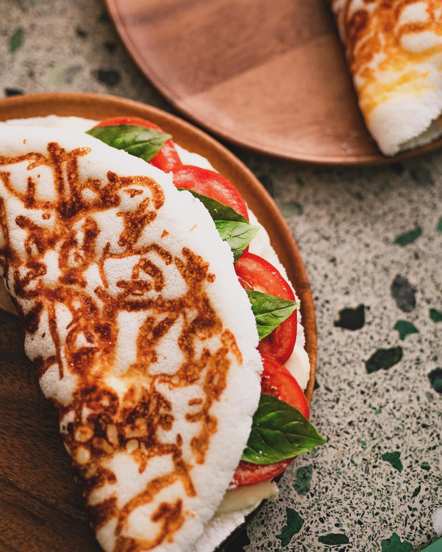 Un sandwich préparé avec des arepas grillées, garni de tomates fraîches et de basilic au restaurant halal La Cai à Bruxelles, Belgique.