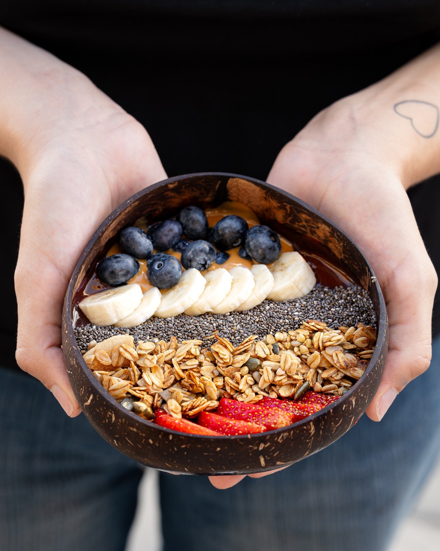 Un bol de smoothie garni de tranches de banane, de myrtilles, de graines de chia, de granola et de fraises au restaurant halal La Cai à Bruxelles, Belgique.