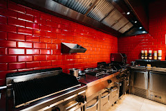 The interior of halal restaurant King Ribs in Gent, Belgium, showing a modern kitchen with red tiled walls and stainless steel appliances.